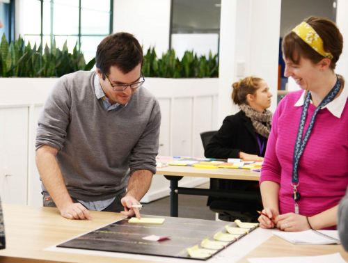Three young professionals working together with post-it notes in an office