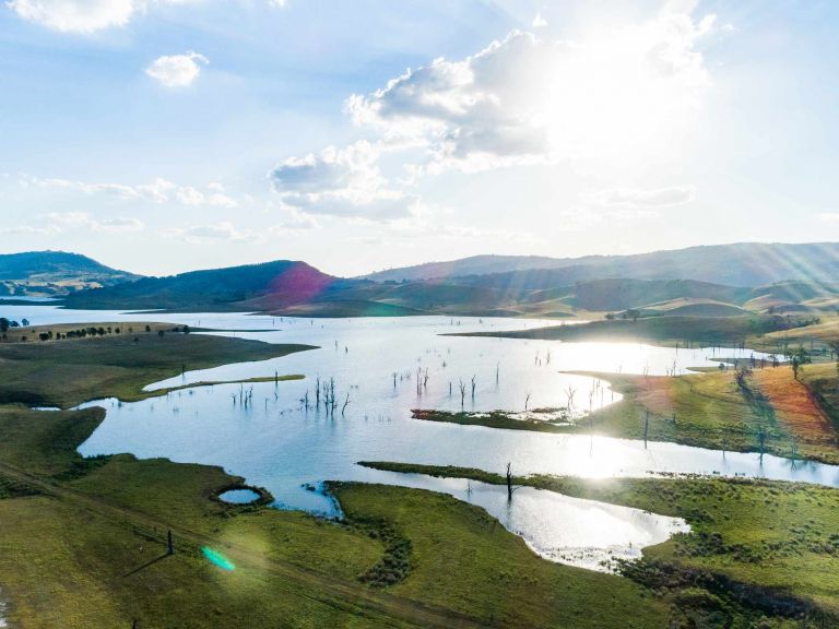 Sun reflecting off large inland lake amid lush green fields