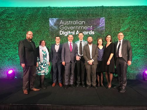 Nine people in dinner clothes at awards ceremony