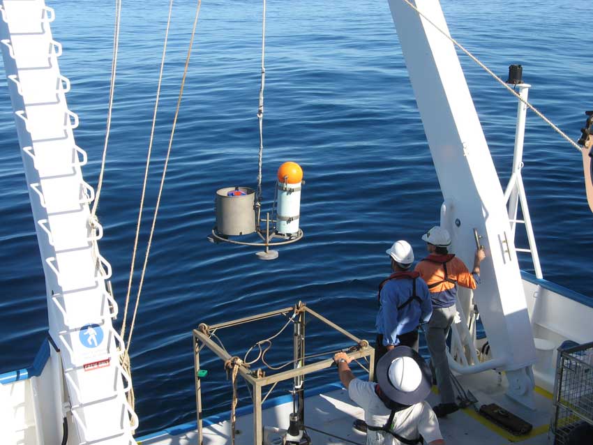 Two cylindrical instruments being lowered over the side of a boat.