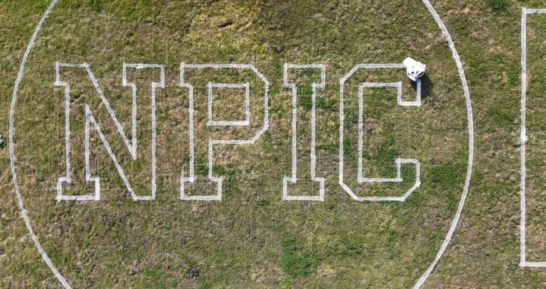 large letters, N P I C,  painted on a sports field